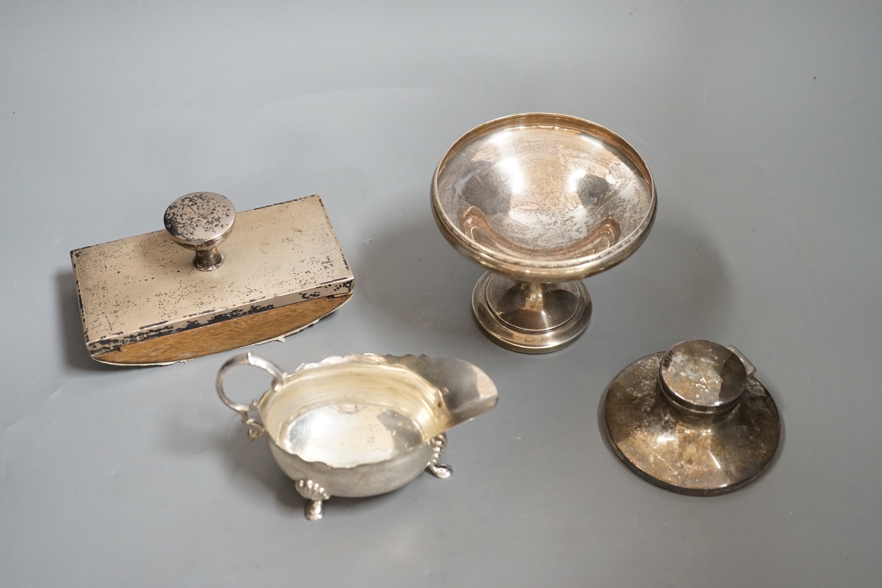 A George VI silver sauceboat, London, 1937, a silver mounted blotter, a silver mounted capstan inkwell and a silver tazze.